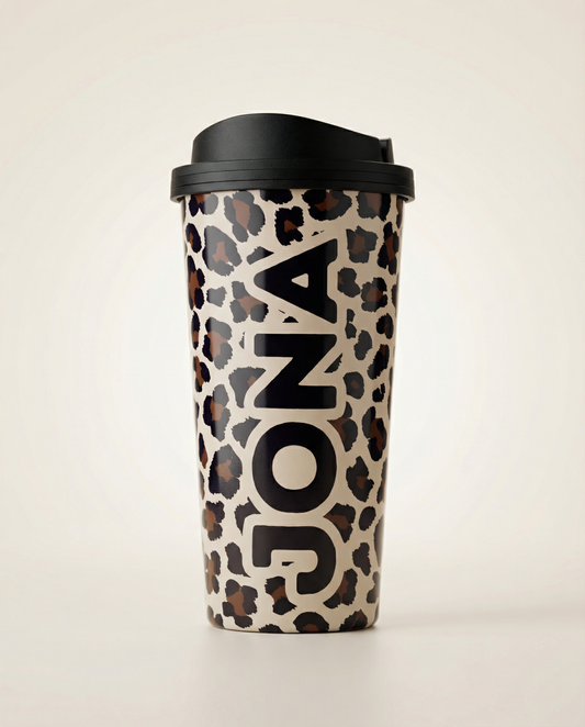 Leopard print travel mug with black lid on a light beige background